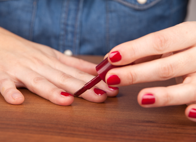 Midsection woman applying red nail polish table