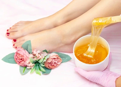Young woman having hair removal procedure leg with sugaring paste salon